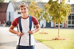 boy standing front of school smiling
