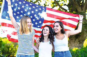 three girls holding up an american flag